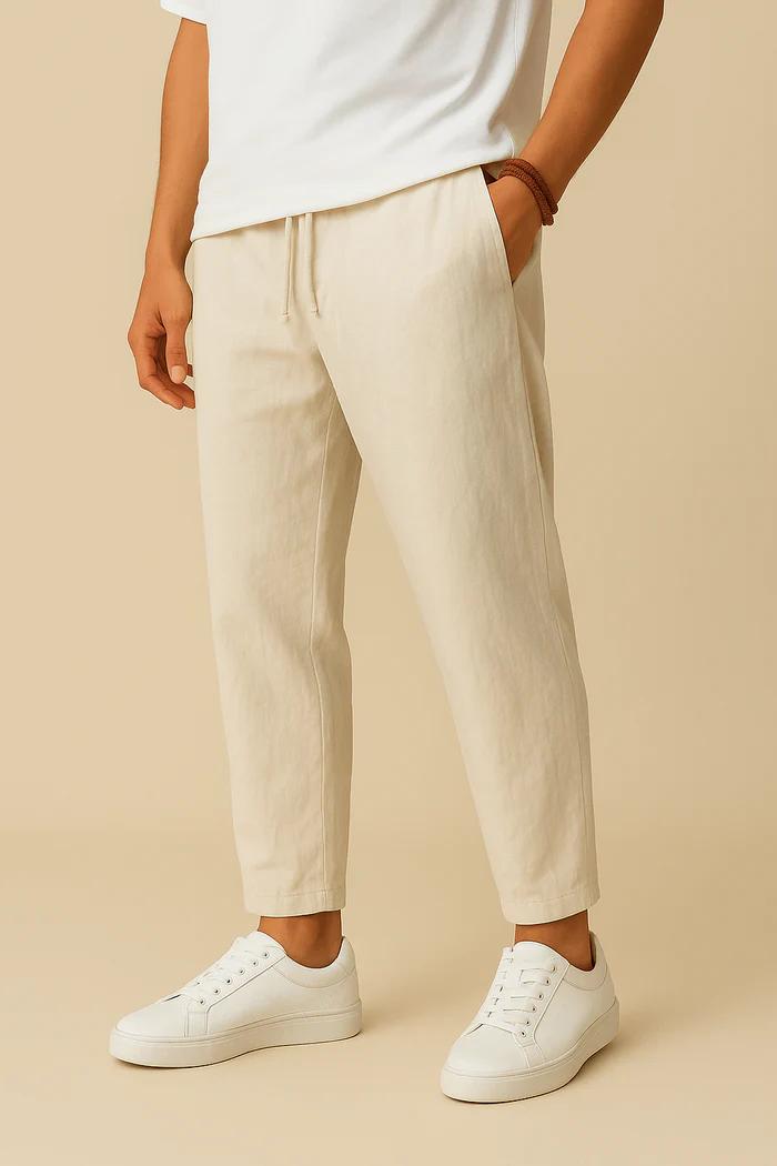 Person wearing beige pants and white sneakers on a beige background